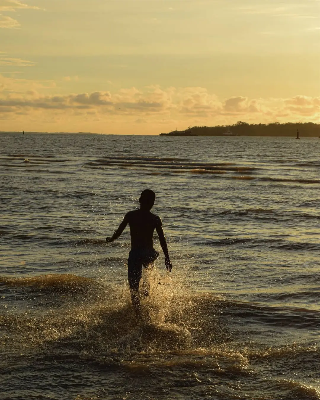 Persona entrando al mar al atardecer